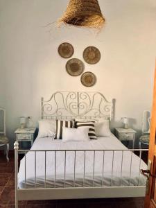 a bedroom with a white bed with plates on the wall at Casita Volcan Lanzarote in Ye