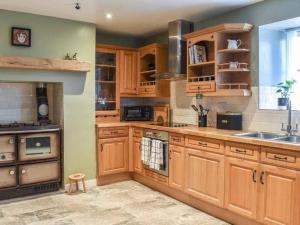 uma grande cozinha com armários de madeira e um lavatório em Cremlyn Lodge em Beaumaris