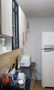 uma cozinha com um balcão, um micro-ondas e um frigorífico em Quarto em Apartamento Centro em Criciúma