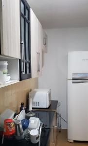 a kitchen with a counter with a microwave and a refrigerator at Quarto em Apartamento Centro in Criciúma