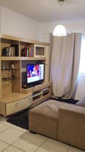 uma sala de estar com uma televisão de ecrã plano e um sofá em Quarto em Apartamento Centro em Criciúma