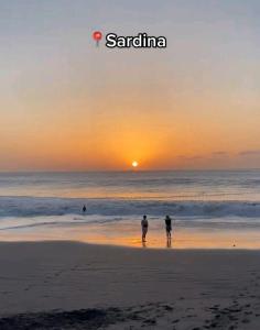 Due persone in piedi sulla spiaggia al tramonto di La casita de Sardina a Sardina