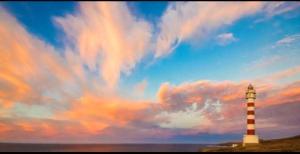 un faro sulla spiaggia con un cielo nuvoloso di La casita de Sardina a Sardina