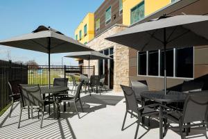 薩利納的住宿－Fairfield Inn & Suites by Marriott Salina，一个带桌椅和遮阳伞的庭院