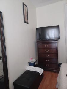 a living room with a dresser and a flat screen tv at The Heiress Hubb in Brooklyn