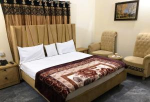 a bedroom with a bed and two chairs at Hotel Air inn in Lahore
