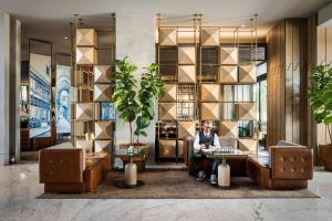 a person sitting in a lobby with a laptop at Hotel Nia, Autograph Collection in Menlo Park