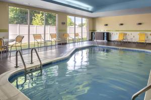 - une piscine avec des chaises et des tables dans un bâtiment dans l'établissement Fairfield Inn & Suites by Marriott New Castle, à New Castle