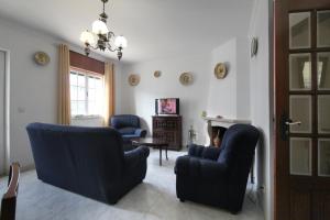 a living room with two blue chairs and a table at Casa da Avó in Vila Nova de Milfontes