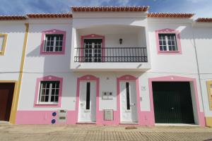 a pink and white house with a balcony at Casa da Avó in Vila Nova de Milfontes