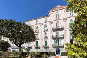a large white building with a tree in front of it at PALAIS DE MENTON - Elegant apartment with sea view in Menton