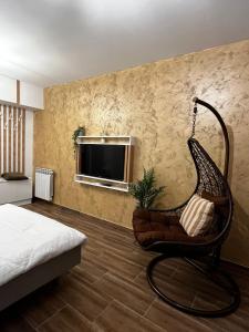 a room with a chair and a television on a wall at One Room Iasi in Iaşi
