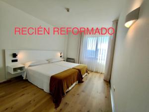 a hotel room with a bed and a sign that reads reign reformambo at Playas de Liencres - Hotel & Apartamentos in Boó de Piélagos