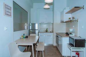 a kitchen with white cabinets and a table with chairs at Acropolis Museum Stylish Apartments in Athens
