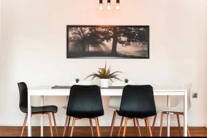 una mesa blanca con 4 sillas y una foto en la pared en Vasilis luxury apartment en Athens