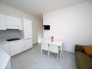 a small white kitchen with a white table and chairs at Apartment Marcello-5 by Interhome in Rosolina Mare