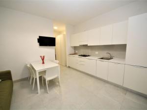 a kitchen with white cabinets and a white table with chairs at Apartment Marcello-5 by Interhome in Rosolina Mare +12 photos