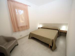 a small bedroom with a bed and a window at Apartment Marcello-5 by Interhome in Rosolina Mare