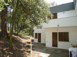 a white house with brown doors and trees at Apartment Marcello-5 by Interhome in Rosolina Mare