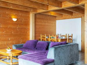 a living room with a purple couch and wooden walls at Chalet Naulaz by Interhome in Val-d'Illiez