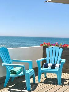 duas cadeiras azuis sentadas num deque perto do oceano em Casa de Chanquete em Viana do Castelo