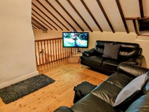 sala de estar con sofá de cuero y TV de pantalla plana en Millers Close Holiday Cottages, en Newcastle