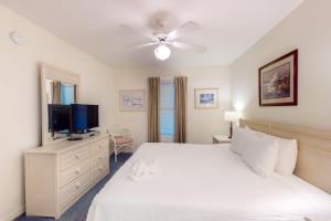 a bedroom with a white bed and a flat screen tv at Islander E 2007 in Fort Walton Beach