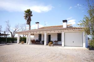 una casa blanca con un garaje y una palmera en La Casilla, en Deltebre