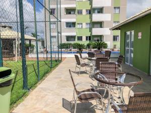 a patio with chairs and a fence with a pool at Apt 300 m da praia próximo ao Beto Carrero in Piçarras