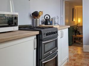 a kitchen with a stove and a microwave at Allington Cottage in Bridport