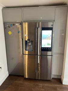 a large stainless steel refrigerator with a television on top at Lovely 3 bedroom house in Borehamwood . in Borehamwood