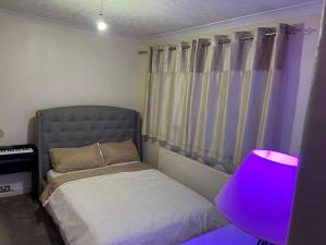 a bedroom with a bed and a purple lamp at Lovely 3 bedroom house in Borehamwood . in Borehamwood