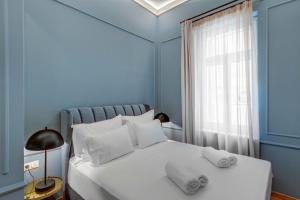 Amare Boutique Suites في إرموبولّي: غرفة نوم زرقاء مع سرير أبيض مع وسادتين