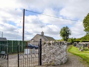 a stone fence in front of a house at Church Cottage in Coupar Angus