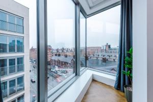 a room with large windows looking out at a city at Hilltop Serviced Apartments - Ancoats in Manchester