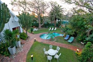 un patio trasero con mesa, sillas y piscina en Africa Beach B&B en Port Elizabeth