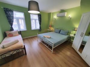 1 dormitorio con paredes verdes, 1 cama y ventana en HANCHO - OLD CITY PLOVDIV Center en Plovdiv