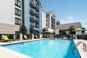 a swimming pool with chairs and a building at SpringHill Suites Houston Hobby Airport in Houston