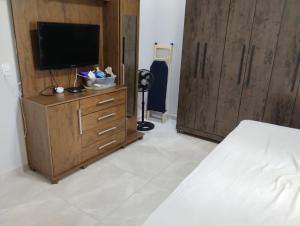 a bedroom with a bed and a tv on a wooden cabinet at Casa Serra da canastra in São João Batista do Glória