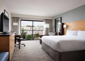 a hotel room with a large bed and a balcony at Sonesta Redondo Beach and Marina in Redondo Beach
