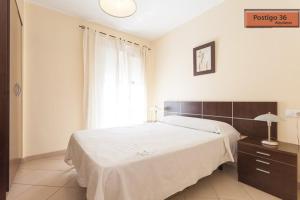 Un dormitorio con una gran cama blanca y una ventana en Apartamentos Postigo 36, en El Puerto de Santa María