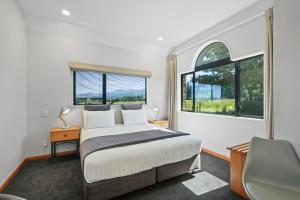 a bedroom with a bed and two windows at Hanmer Springs Scenic Views Motel in Hanmer Springs