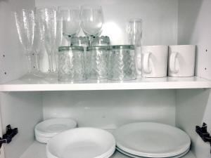 a white shelf with glass vases and plates on it at Studio Apartment in Auckland CBD in Auckland