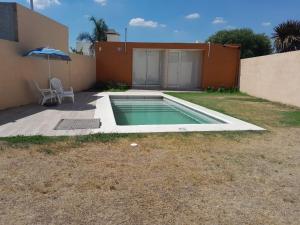 una piscina con sombrilla junto a una casa en CASA QUINTA La Donna con DESAYUNO en Villa María