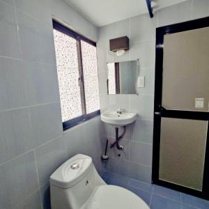 a bathroom with a white toilet and a sink at Capaclan Centro Private Room in Romblon