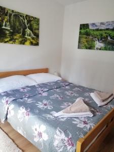 a bed in a bedroom with two pictures on the wall at Guest House Končar in Plitvička Jezera