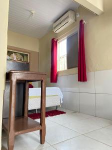 貝貝里比的住宿－Cantinho Morro Branco，一间设有床铺和红色窗帘的窗户的客房