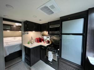 a small kitchen with a refrigerator and a bed at Lake front RV experience close to port Canaveral and Kennedy space center in Titusville