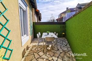 d'une terrasse avec une table et des chaises à côté d'un mur vert. dans l'établissement La Belle Agapanthe-Iris - Maison de ville à Limoges, à Limoges