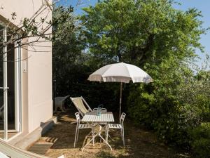 a table and chairs under an umbrella on a patio at Casottino presso residenza Rosso di Sera in Capoliveri